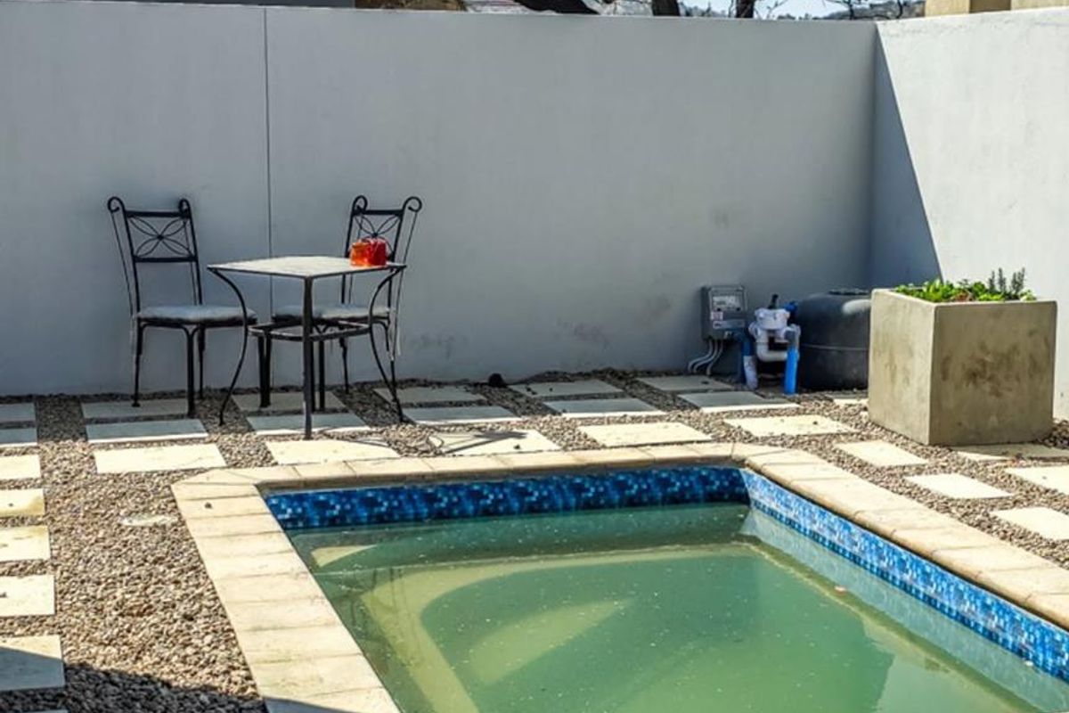 A small plunge pool area featuring a paved surround, gravel landscaping, and a high boundary wall for privacy.