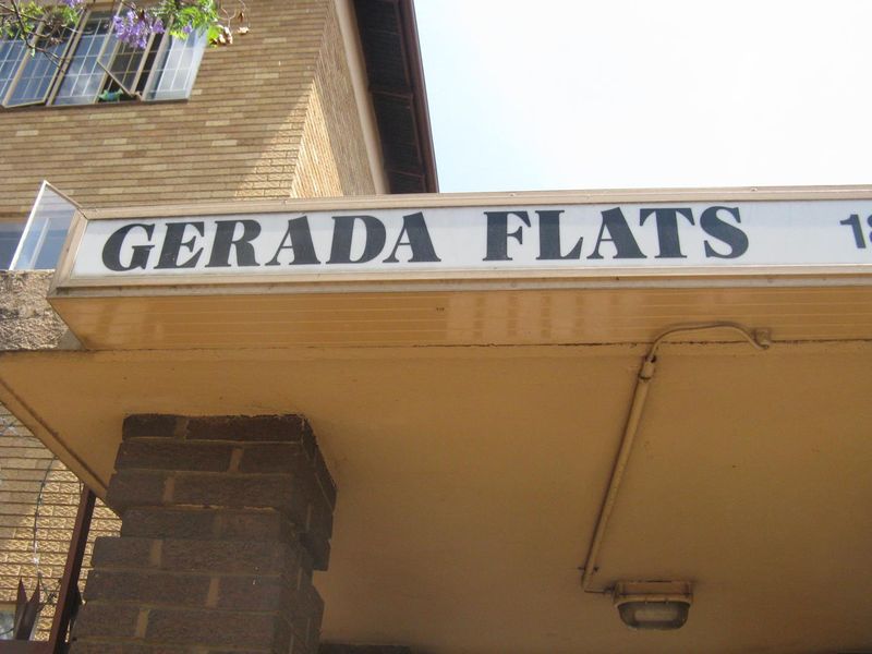 Exterior view of the entrance canopy and brick facade of Gerada Flats apartment building.