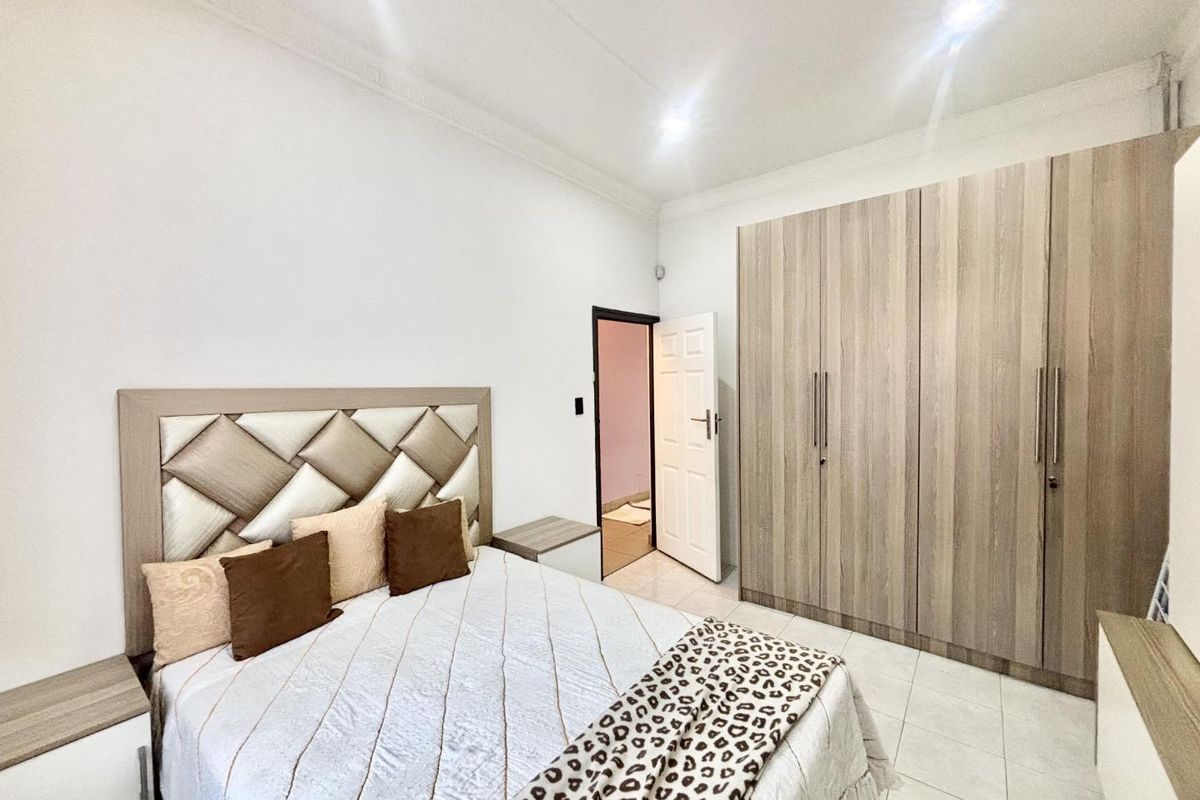 A well-maintained bedroom featuring neutral tiled flooring, modern built-in cupboards, and recessed ceiling lighting.