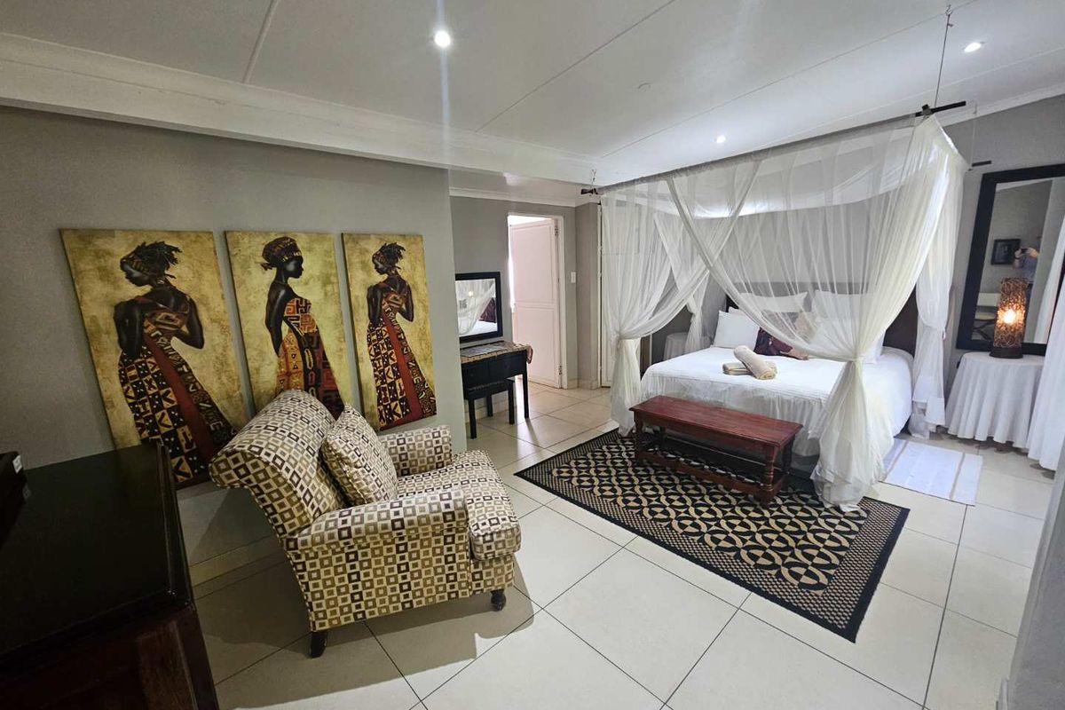 A spacious bedroom featuring tiled flooring, recessed ceiling lighting, and a four-poster bed frame with canopy curtains.