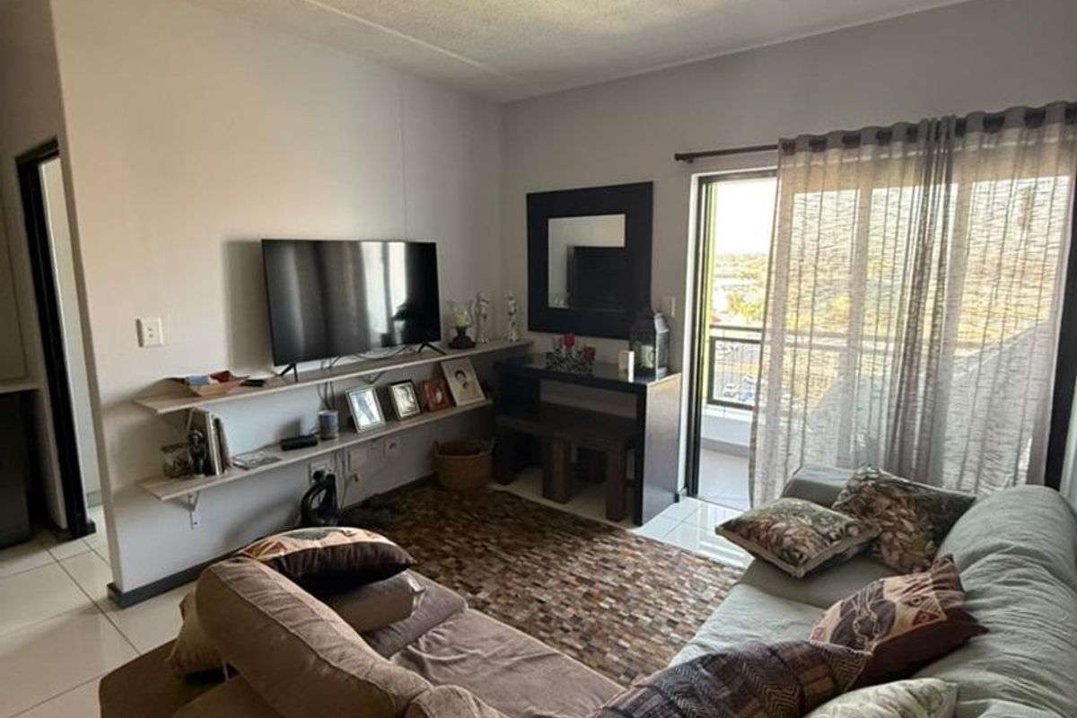 A comfortable living room featuring tiled flooring, built-in shelving, and a sliding glass door providing access to an outdoor balcony area.