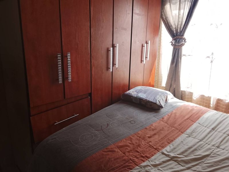 A bedroom featuring a large, full-height built-in wooden wardrobe with modern metal handles.