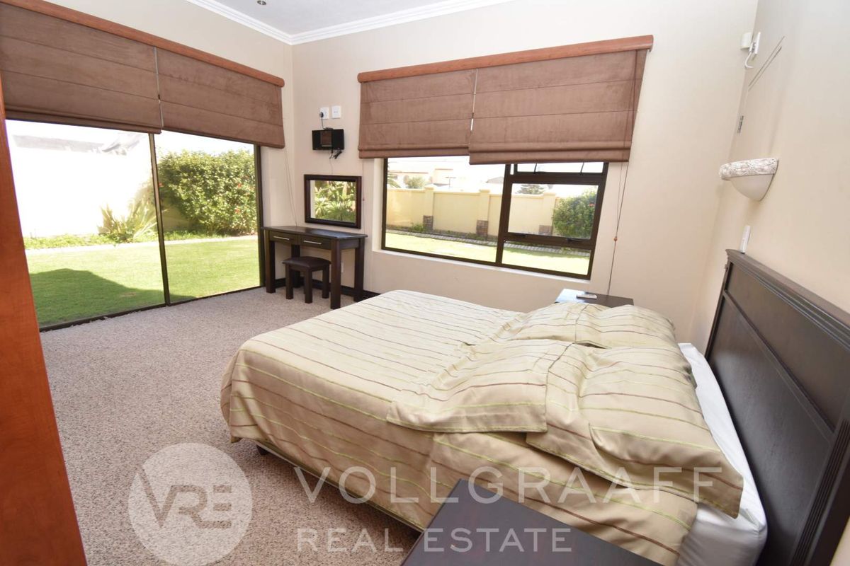 Spacious bedroom featuring large sliding glass doors providing direct access to the garden, carpeted flooring, and neutral wall finishes.