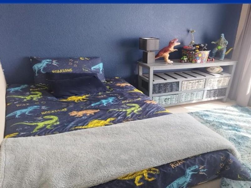 A bedroom featuring a dark blue accent wall and neutral flooring, suitable for a child's room or guest bedroom.