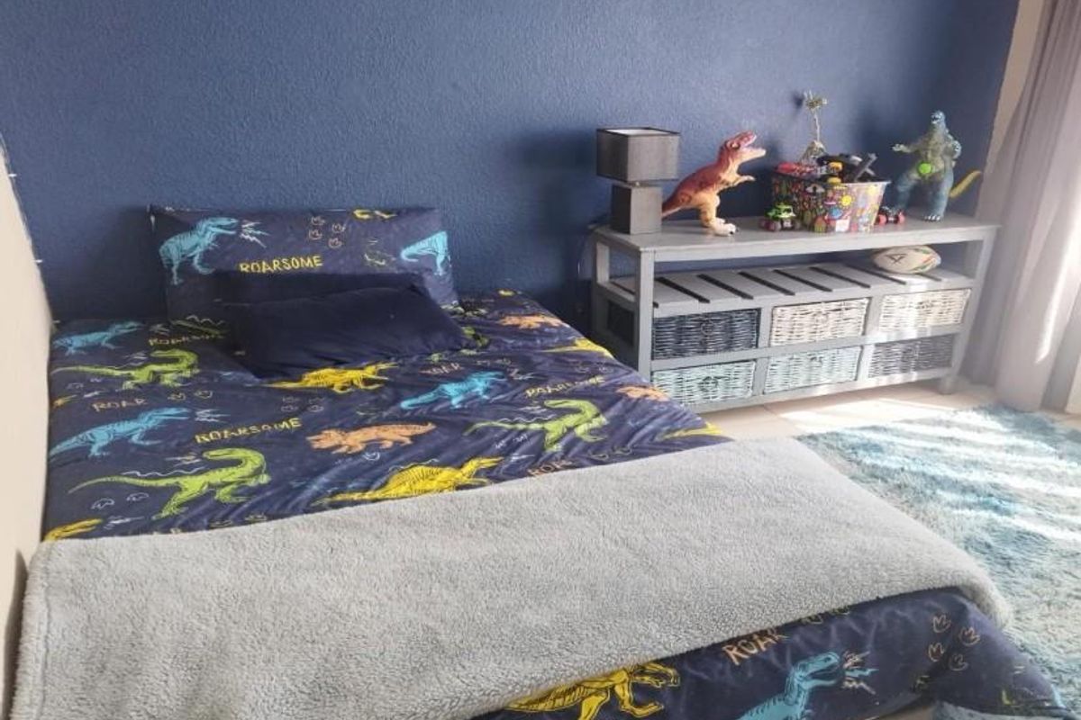 A bedroom featuring a dark blue accent wall and neutral flooring, suitable for a child's room or guest bedroom.