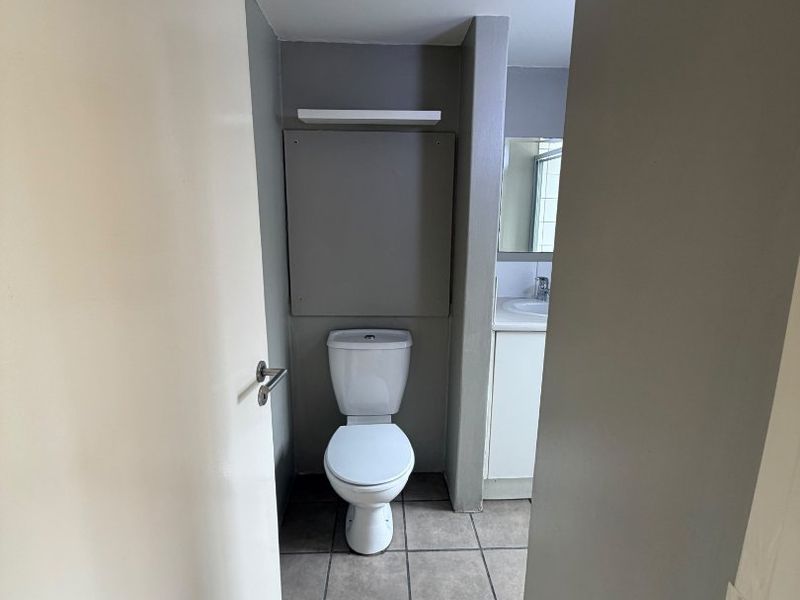 A functional bathroom featuring tiled flooring, a standard toilet, and a vanity with a basin.