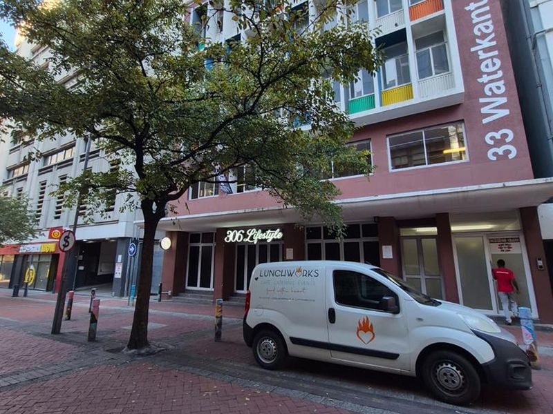 Street-level view of the 33 Waterkant office building facade, featuring a multi-story exterior with colorful architectural accents and a paved pedestrian entrance area.