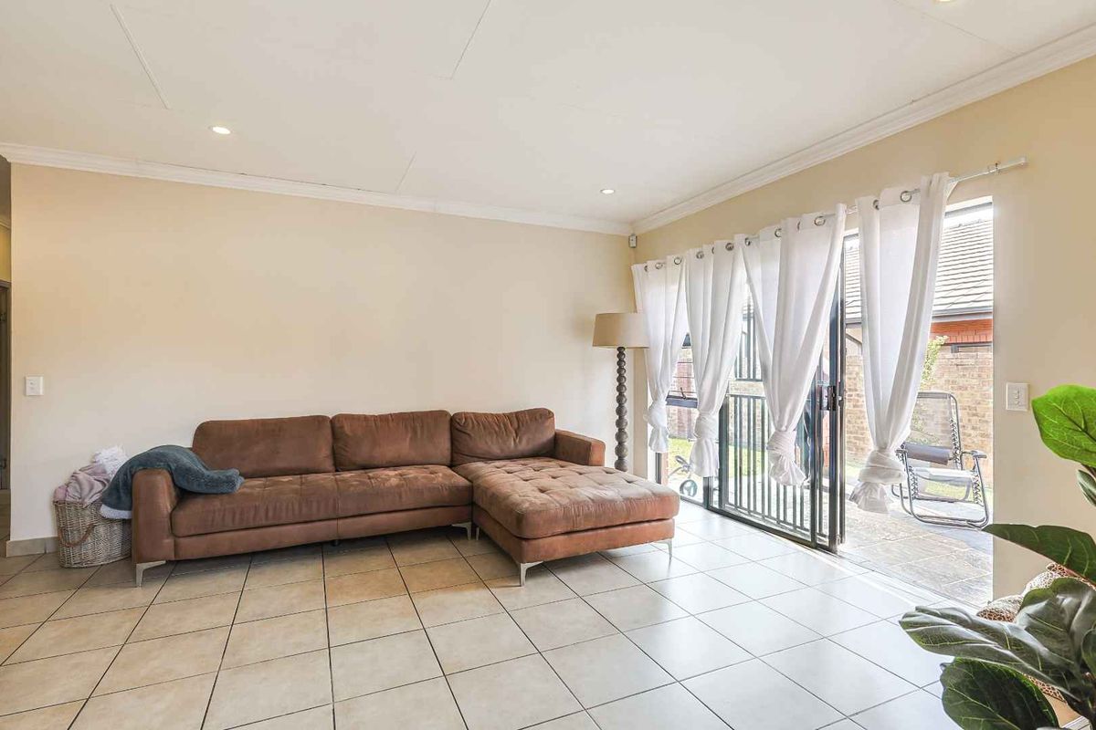 Spacious living room featuring neutral tiled flooring, recessed ceiling lighting, and large sliding glass doors providing direct access to the outdoor patio area.