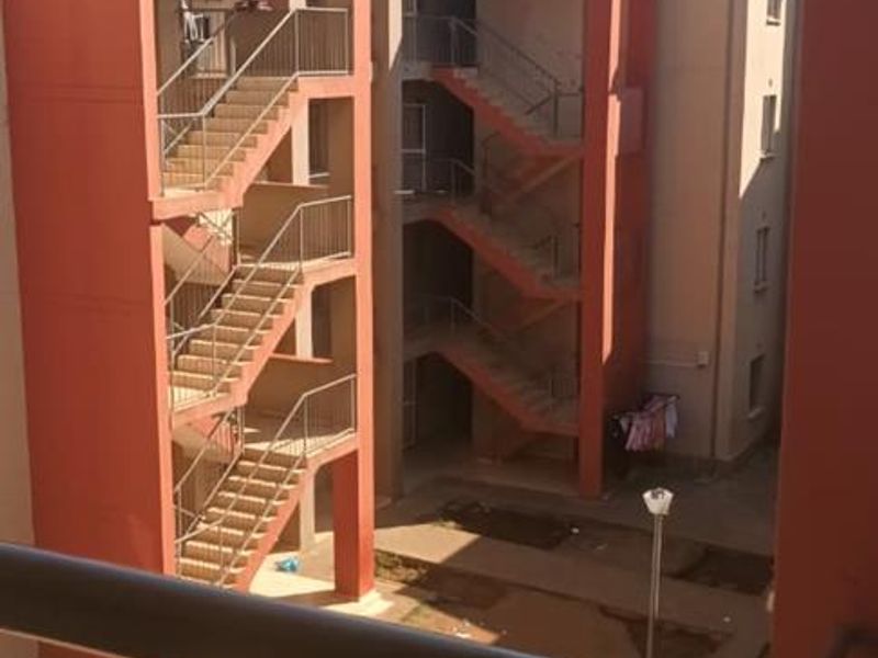 View from a balcony overlooking a communal courtyard and external staircases of a townhouse complex.