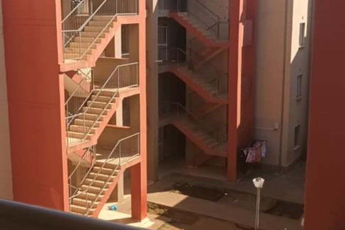 View from a balcony overlooking a communal courtyard and external staircases of a townhouse complex.