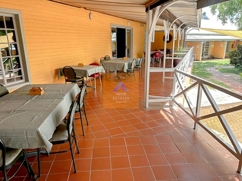 A spacious covered outdoor patio area featuring terracotta tiled flooring and a metal safety railing, suitable for guest dining or relaxation.