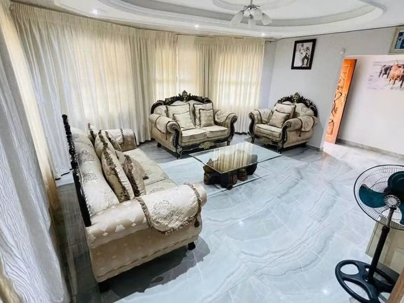 A spacious living room featuring polished tiled flooring and a decorative recessed ceiling with integrated lighting.