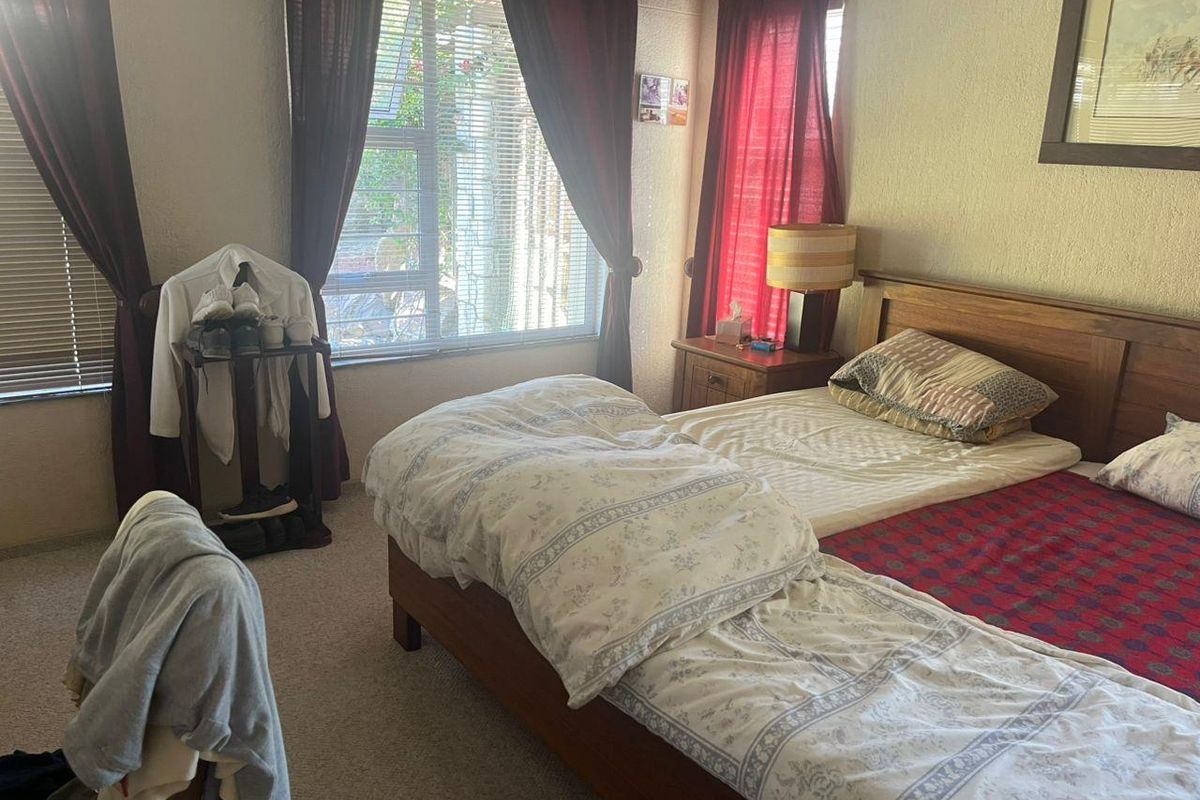A bedroom featuring carpeted flooring and large windows with blinds, providing natural light to the space.