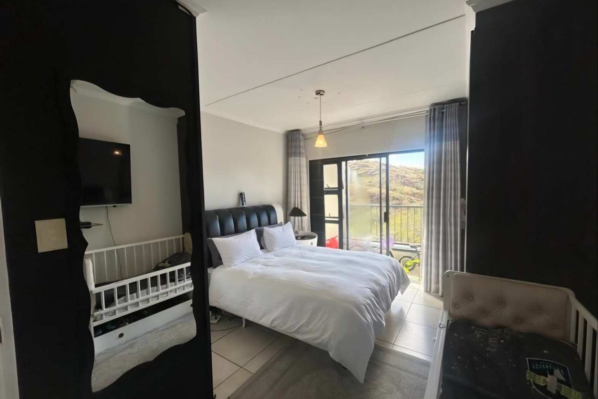 A bedroom featuring tiled flooring and sliding glass doors that open onto a balcony with scenic views.