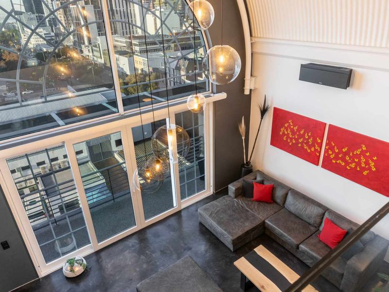 Spacious living area featuring a dramatic vaulted ceiling, polished concrete floors, and a large arched window offering expansive city views.