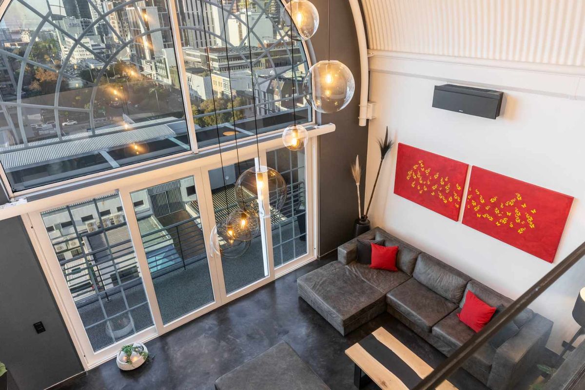 Spacious living area featuring a dramatic vaulted ceiling, polished concrete floors, and a large arched window offering expansive city views.
