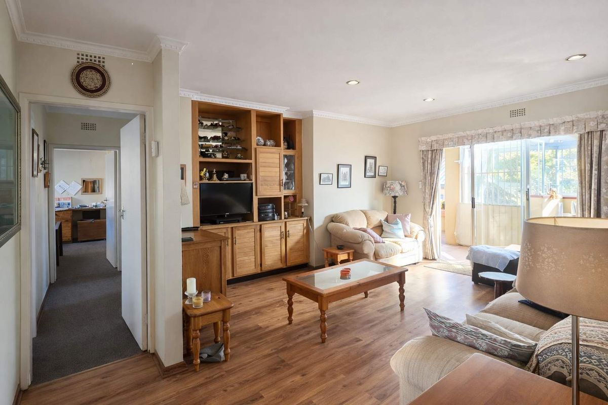 Spacious living room featuring built-in wooden cabinetry, recessed lighting, and direct access to a balcony through sliding glass doors.