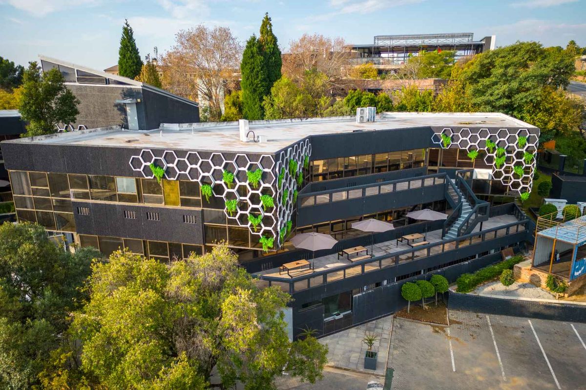 Aerial view of a modern office building featuring a unique honeycomb facade design, external terrace, and dedicated parking area.