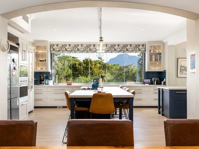 A modern, well-appointed kitchen featuring a central island, high-end cabinetry, integrated appliances, and a large window offering scenic mountain views.