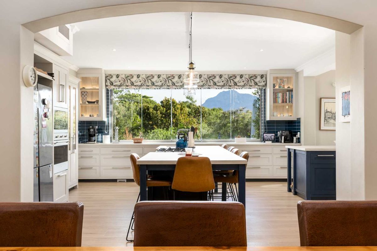 A modern, well-appointed kitchen featuring a central island, high-end cabinetry, integrated appliances, and a large window offering scenic mountain views.