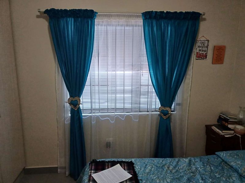 A bedroom featuring a window with venetian blinds and curtain rod, providing natural light and a functional layout.