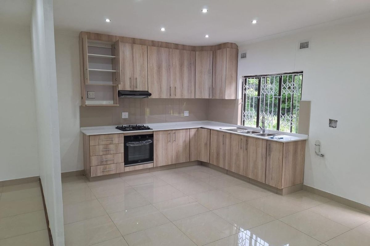 Modern kitchen featuring light wood-grain cabinetry, gas hob, under-counter oven, and tiled flooring. The space is clean, bright, and ready for final finishing touches.