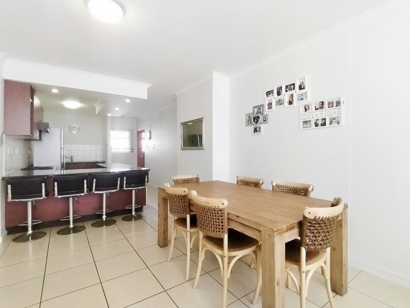 Open-plan living and dining area featuring a functional kitchen with granite countertops, breakfast bar, and neutral ceramic floor tiles throughout.