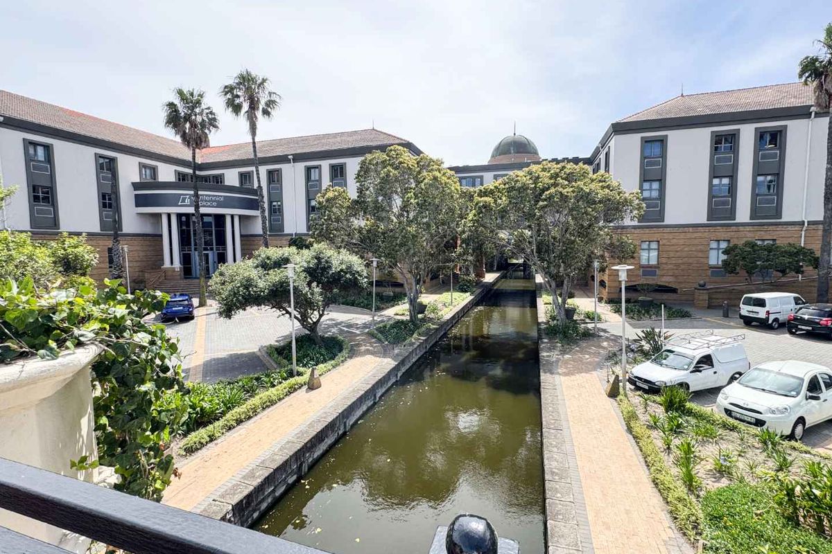 Exterior view of a professional office complex featuring a central canal, landscaped gardens, and paved walkways between multi-story buildings.