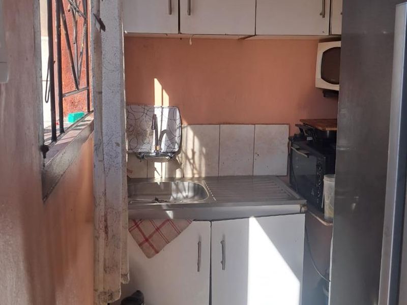 A compact scullery area featuring a stainless steel sink, built-in cabinetry, and tiled splashback, providing functional prep and wash-up space.