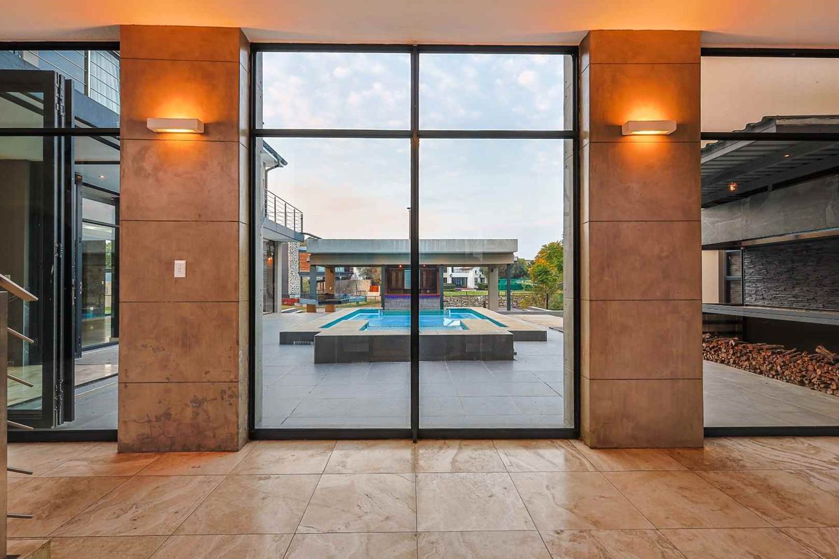 Spacious living area featuring large floor-to-ceiling windows with direct views of the outdoor patio and swimming pool area.
