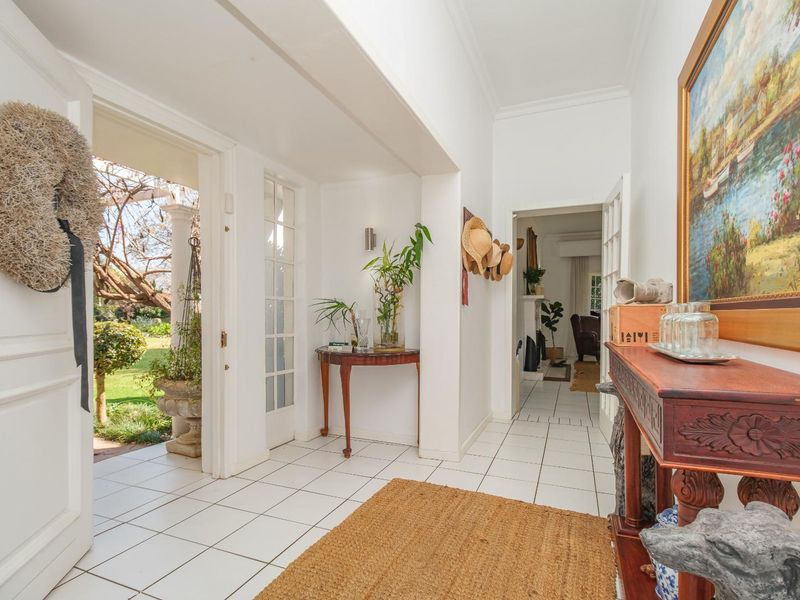 Bright and welcoming entrance hall featuring white tiled flooring, classic coving, and direct access to the garden through a glass-paneled door.