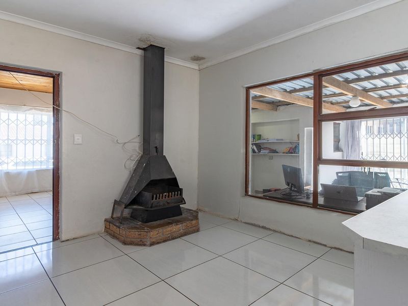 Living area featuring tiled flooring, a central freestanding fireplace, and large windows looking into an adjacent room.