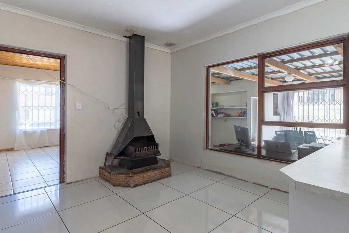 Living area featuring tiled flooring, a central freestanding fireplace, and large windows looking into an adjacent room.