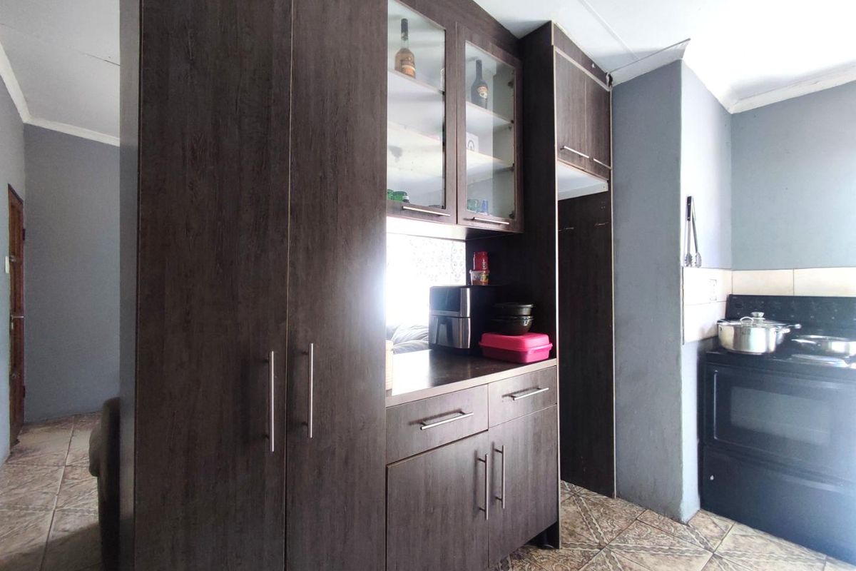 Kitchen area featuring dark wood-look cabinetry, glass-front display cupboards, and a built-in stove space with tiled flooring.