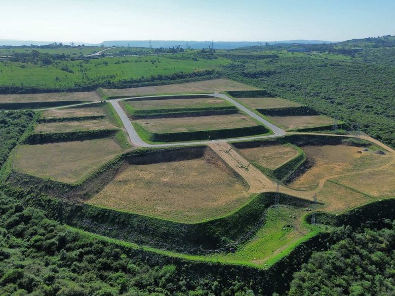 Aerial view of a large industrial development site featuring terraced plots and established internal road infrastructure surrounded by natural landscape.