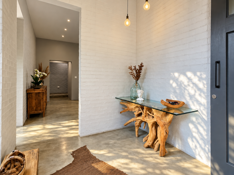 A bright and modern entrance hall featuring polished concrete floors, crisp white painted brick walls, and stylish pendant lighting.