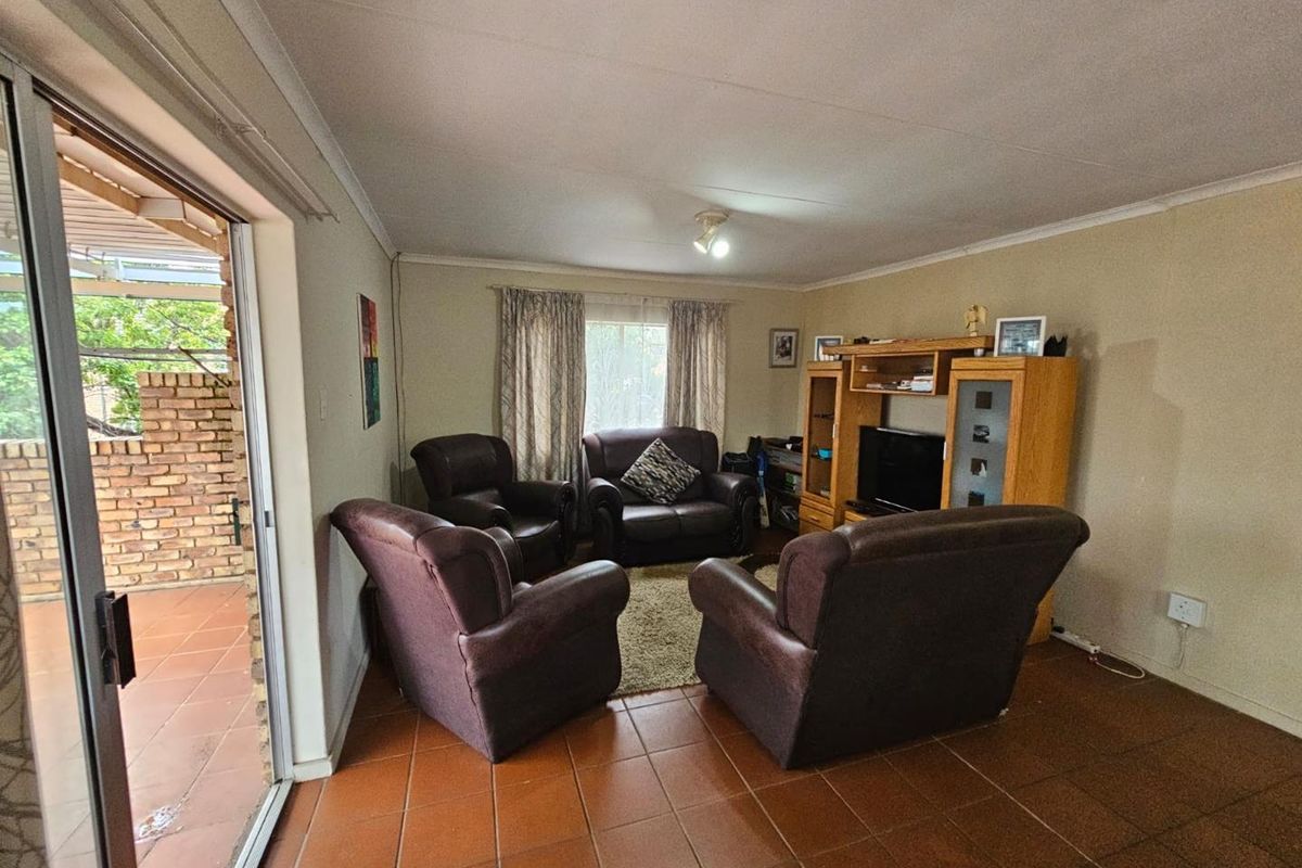 A living room featuring terracotta floor tiles and sliding glass doors providing direct access to an outdoor patio area.