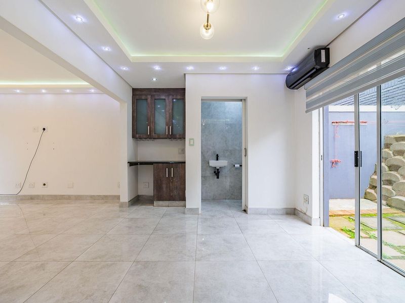 Spacious open-plan living area featuring modern tiled floors, recessed ceiling lighting, built-in cabinetry, and direct access to a private outdoor patio area.