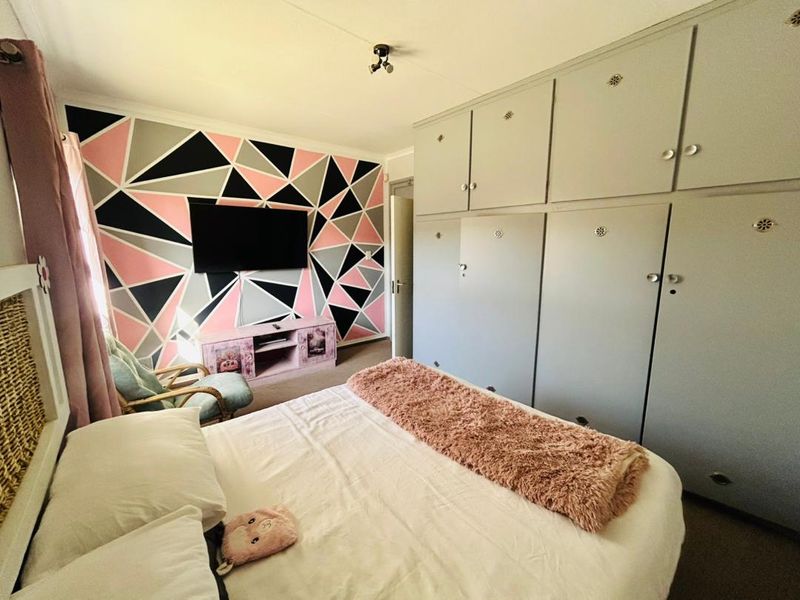A bedroom featuring extensive built-in floor-to-ceiling cupboards and a decorative geometric accent wall.