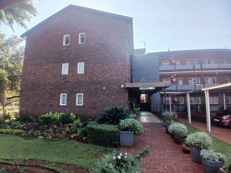 Front elevation of the Overberg apartment complex featuring a brick facade, covered entrance walkway, and landscaped garden area.
