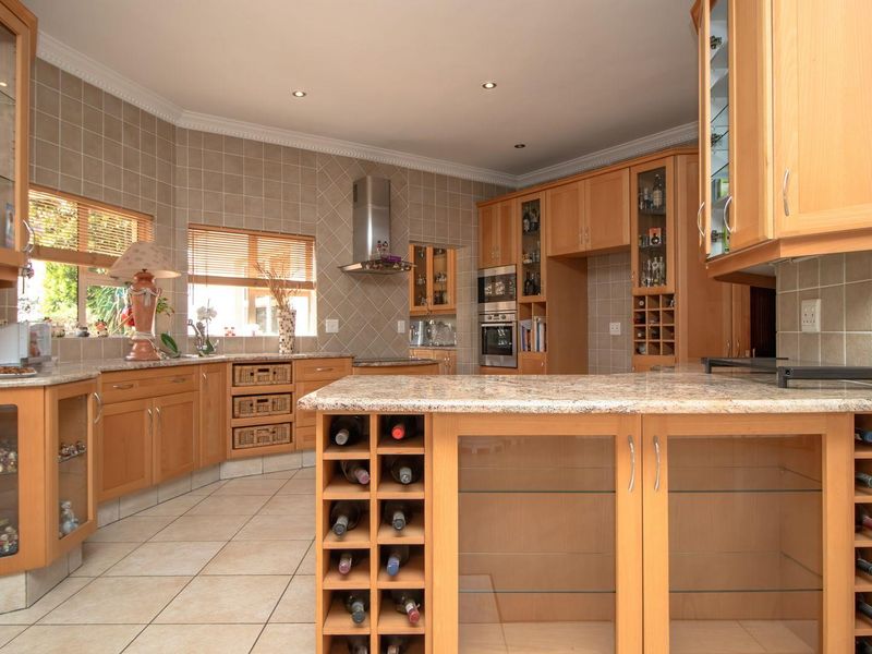 Spacious kitchen featuring light wood cabinetry, granite countertops, integrated wine storage, and tiled finishes throughout.