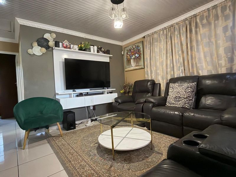 A comfortable living room featuring tiled flooring, decorative ceiling molding, and a built-in media console unit.