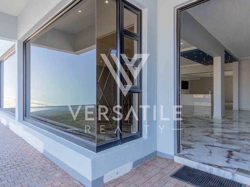 A modern covered patio area featuring large aluminium-framed windows and polished marble-look floor tiles, providing a seamless transition to the interior living space.