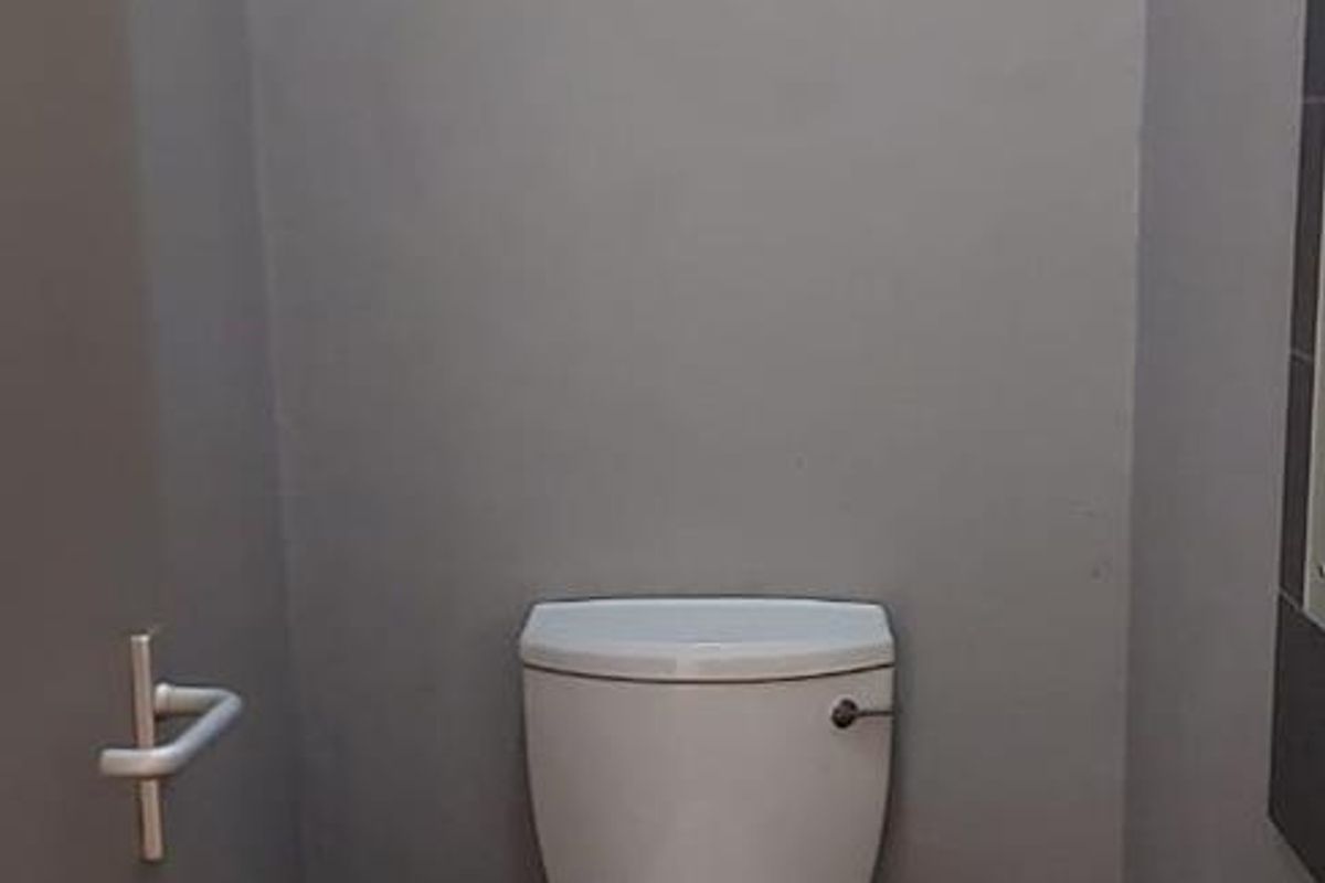 A compact guest bathroom featuring a standard toilet and a wall-mounted basin with dark floor tiling.