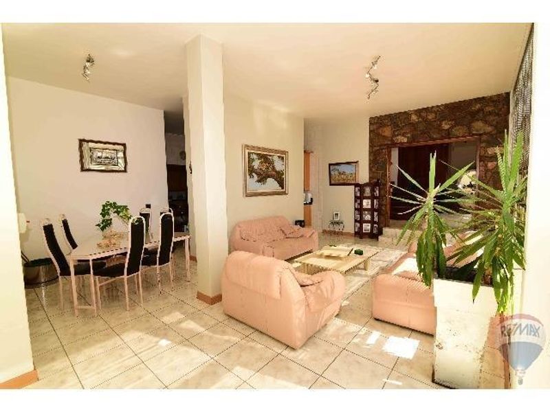 Open plan living and dining area featuring tiled flooring and a distinctive stone feature wall.