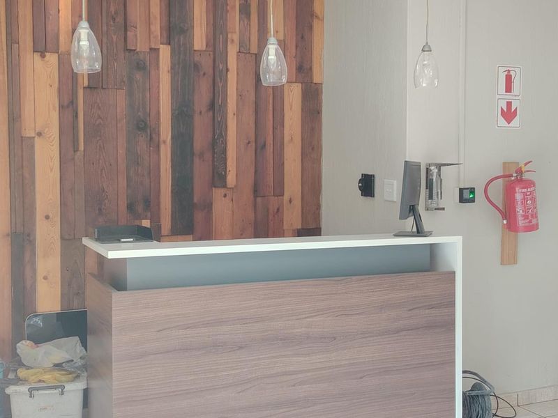 A professional reception area featuring a modern built-in desk, decorative timber wall paneling, and essential fire safety equipment.