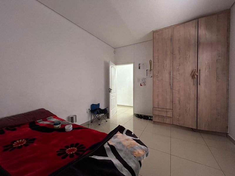 A bedroom featuring tiled flooring and a large built-in wooden wardrobe with integrated storage.
