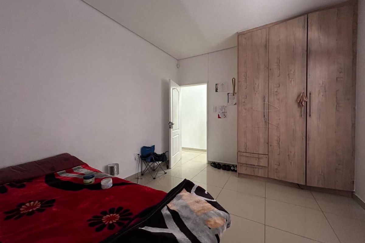 A bedroom featuring tiled flooring and a large built-in wooden wardrobe with integrated storage.