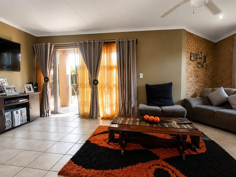 A comfortable living room featuring tiled flooring, an exposed brick accent wall, and a sliding glass door providing access to the outdoor area.