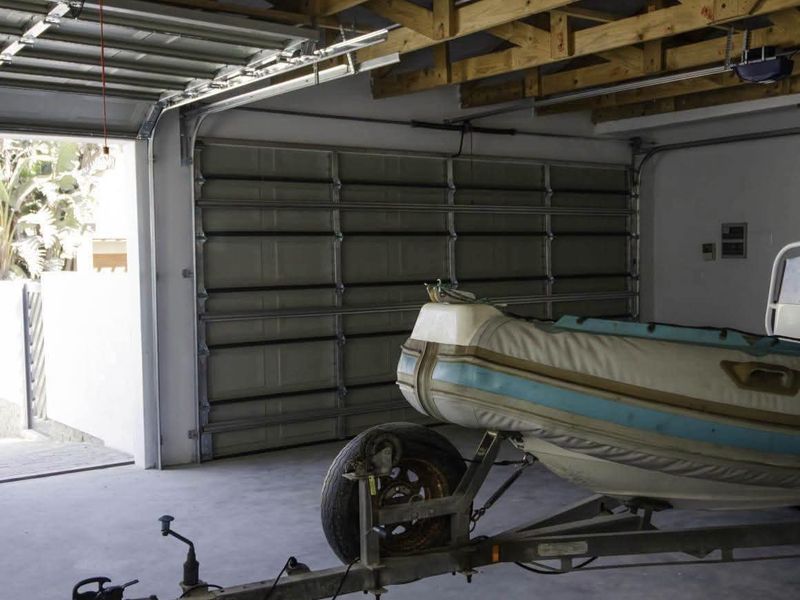 Spacious double garage featuring exposed timber roof trusses, concrete flooring, and an automated sectional garage door.